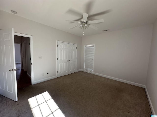 unfurnished bedroom with ceiling fan, a closet, and dark colored carpet