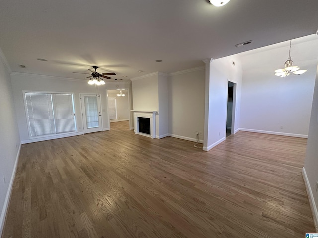 unfurnished living room with wood-type flooring, ceiling fan with notable chandelier, and ornamental molding