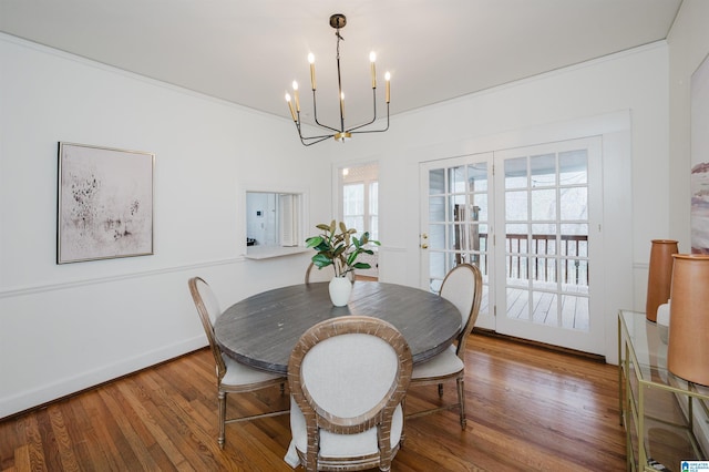 dining area featuring hardwood / wood-style floors, ornamental molding, and an inviting chandelier