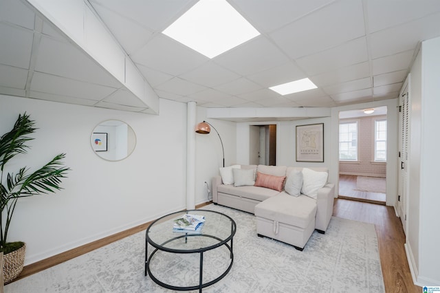 living room featuring a drop ceiling and light wood-type flooring