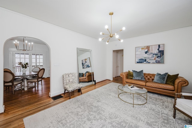 living room featuring wood-type flooring, ornamental molding, and a notable chandelier