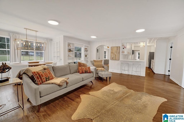 living room with built in shelves and dark wood-type flooring