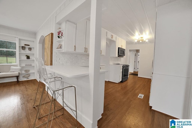 kitchen with a kitchen bar, white cabinetry, dark wood-type flooring, and electric stove