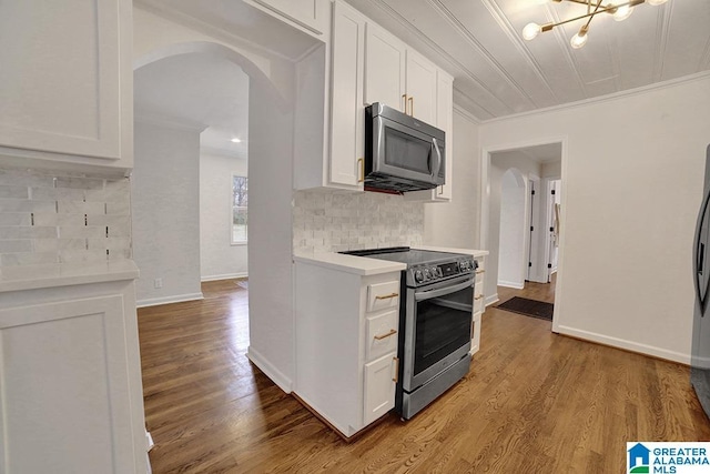 kitchen featuring white cabinetry, crown molding, appliances with stainless steel finishes, and tasteful backsplash