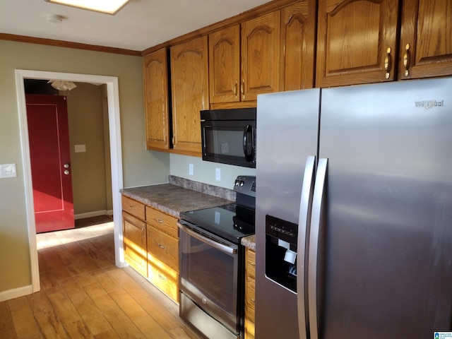 kitchen with ornamental molding, appliances with stainless steel finishes, and light hardwood / wood-style flooring