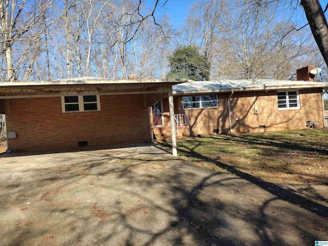 rear view of property featuring a carport and a lawn