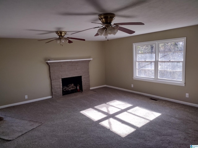 unfurnished living room with a stone fireplace, ceiling fan, and carpet floors