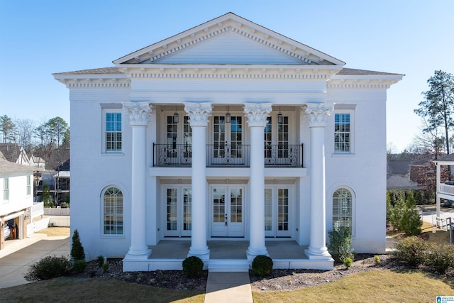 neoclassical home with french doors, a balcony, and a porch