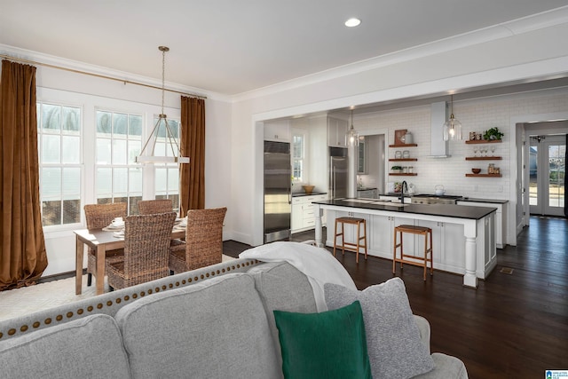 living room with sink, crown molding, and dark wood-type flooring