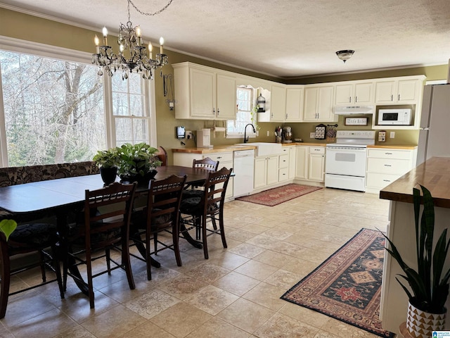 kitchen with white appliances, crown molding, sink, decorative light fixtures, and white cabinetry