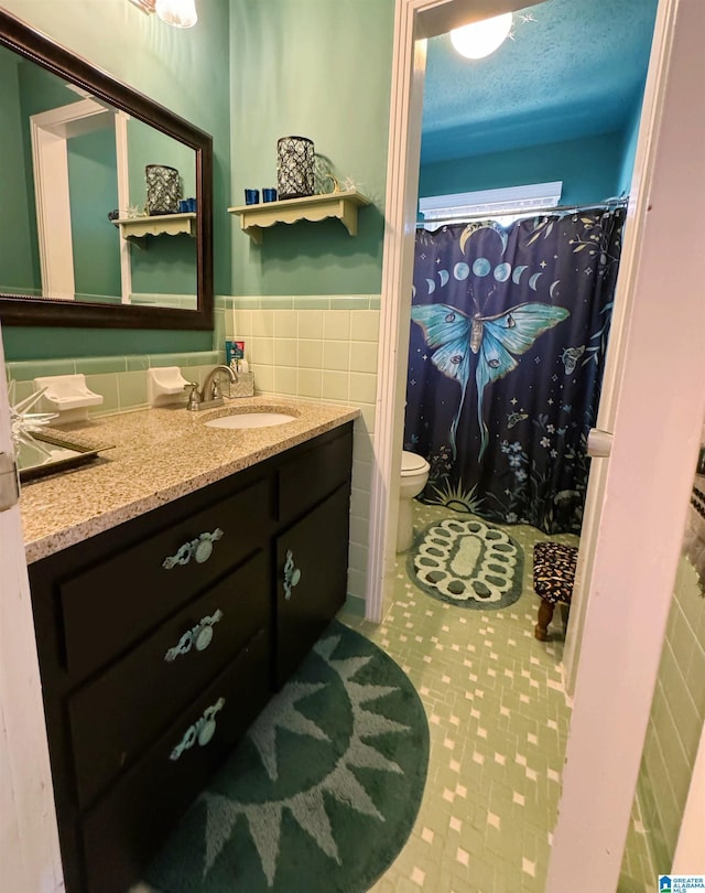 bathroom with vanity, tile patterned flooring, toilet, tile walls, and a textured ceiling