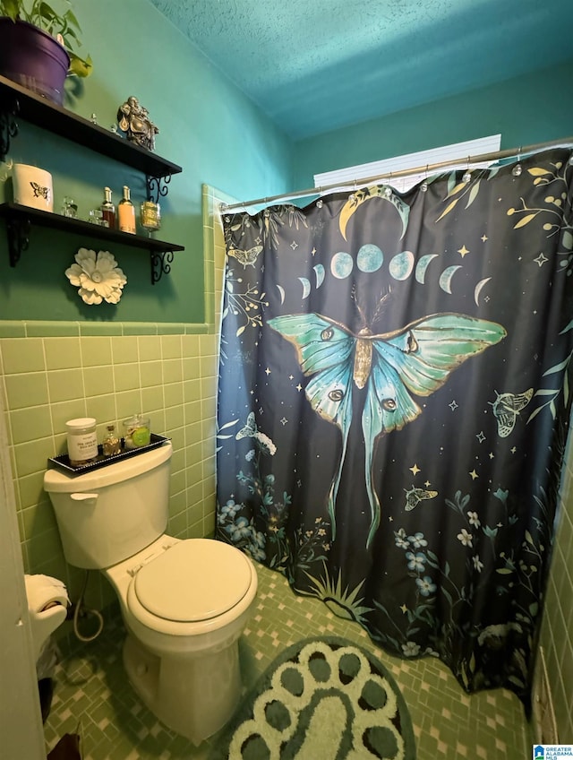 bathroom featuring a textured ceiling, curtained shower, toilet, and tile walls