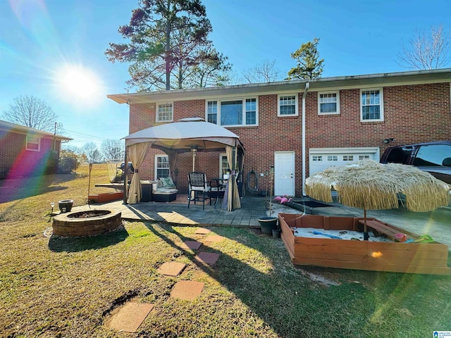 rear view of property featuring a gazebo, a lawn, a patio, and an outdoor fire pit