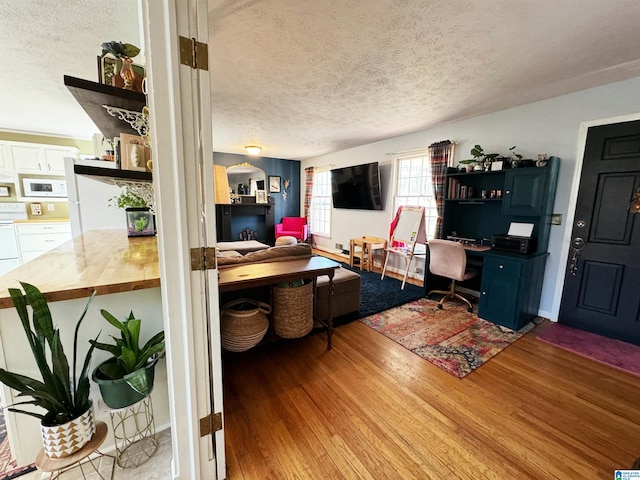 living room with washer and clothes dryer, wood-type flooring, and a textured ceiling