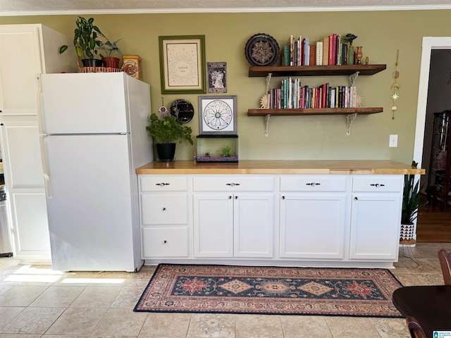 kitchen with white cabinets, light tile patterned floors, and white refrigerator