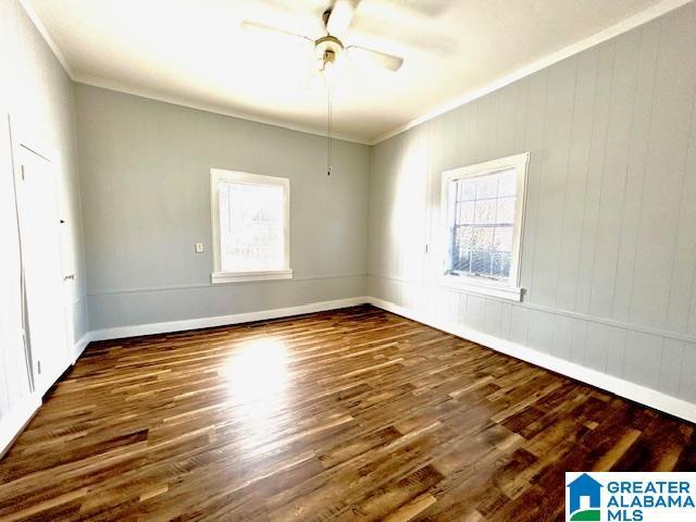 empty room with ceiling fan, dark wood-type flooring, and ornamental molding