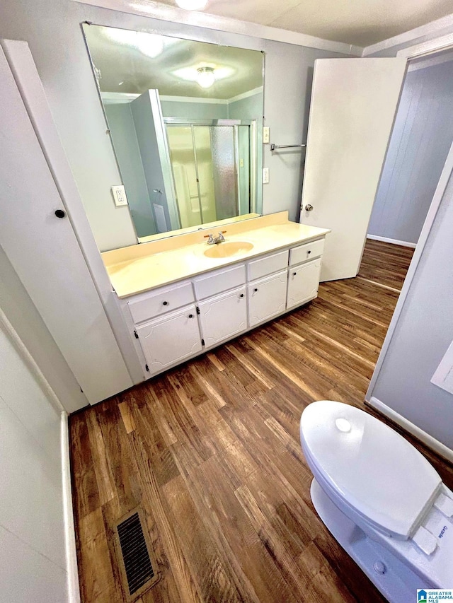 bathroom featuring vanity, crown molding, toilet, walk in shower, and wood-type flooring