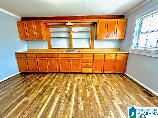 kitchen with ornamental molding, sink, and light hardwood / wood-style flooring