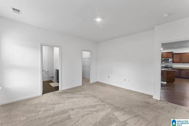 unfurnished bedroom featuring light colored carpet, connected bathroom, a closet, and a walk in closet