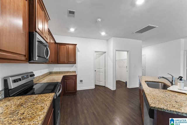 kitchen featuring stainless steel appliances, dark hardwood / wood-style flooring, light stone counters, and sink