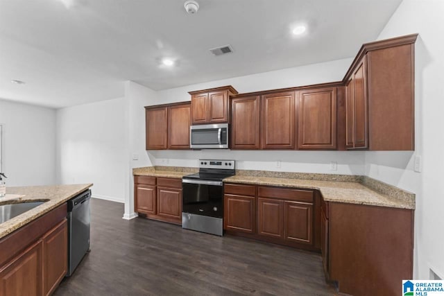 kitchen featuring stainless steel appliances, dark hardwood / wood-style flooring, light stone counters, and sink