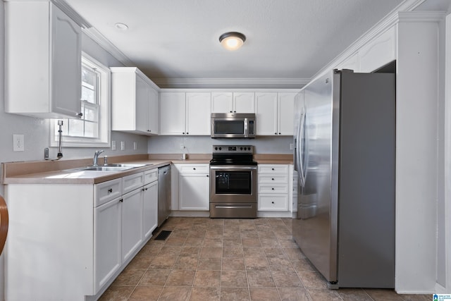 kitchen featuring stainless steel appliances, crown molding, white cabinets, and sink