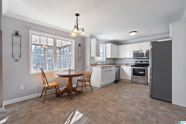 kitchen featuring white cabinets, appliances with stainless steel finishes, sink, hanging light fixtures, and crown molding