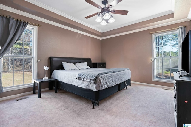 carpeted bedroom featuring ceiling fan, ornamental molding, and a raised ceiling