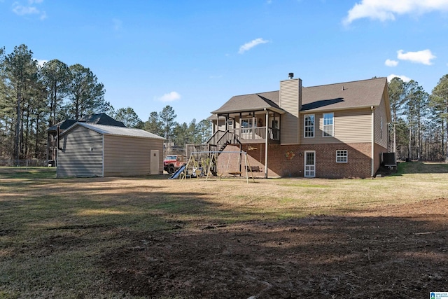 back of property with a playground, a shed, and a yard