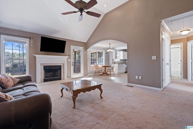 living room featuring ceiling fan, light colored carpet, crown molding, and high vaulted ceiling