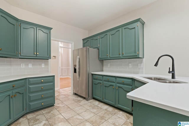 kitchen featuring sink, tasteful backsplash, green cabinets, stainless steel fridge, and light tile patterned floors