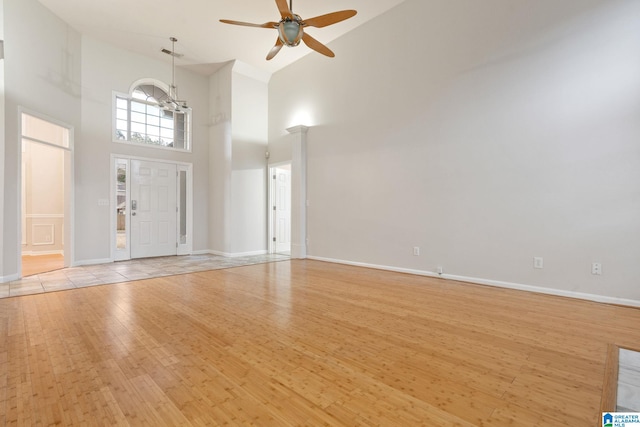 entryway with light hardwood / wood-style flooring, high vaulted ceiling, and ceiling fan with notable chandelier