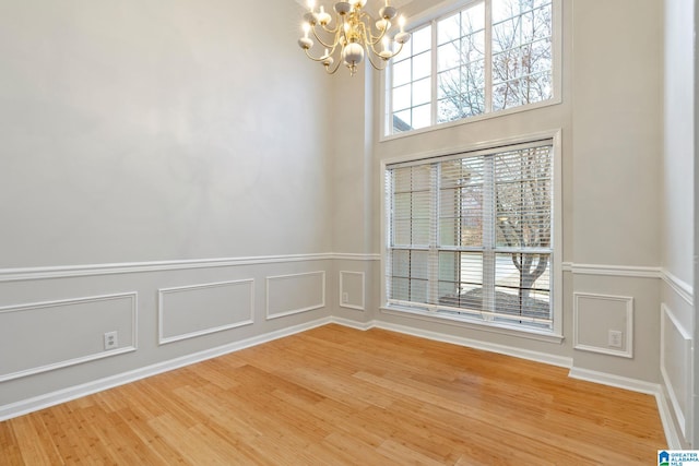 empty room featuring a chandelier, hardwood / wood-style flooring, and plenty of natural light