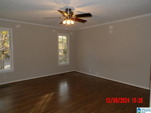 empty room with a healthy amount of sunlight, dark hardwood / wood-style floors, and ornamental molding