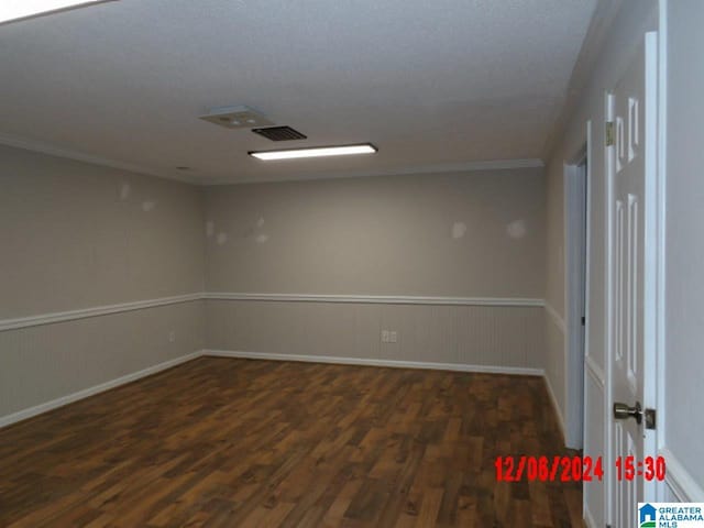 unfurnished room with crown molding, dark wood-type flooring, and a textured ceiling