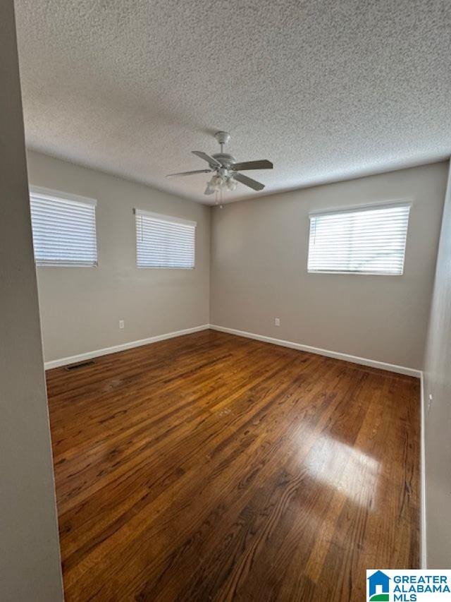 unfurnished room with a textured ceiling, ceiling fan, and dark wood-type flooring