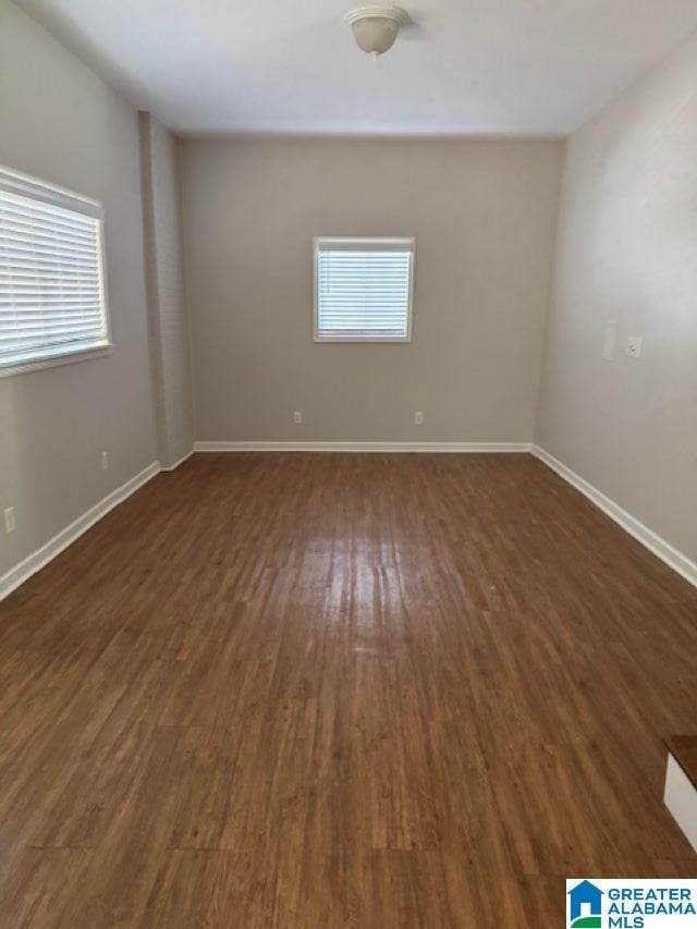 spare room with dark hardwood / wood-style floors and plenty of natural light