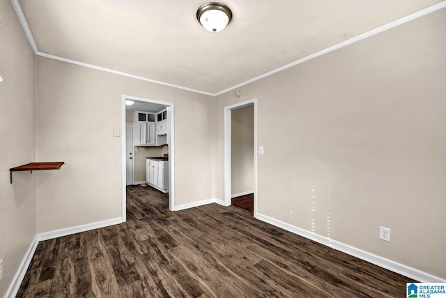 spare room with crown molding and dark wood-type flooring