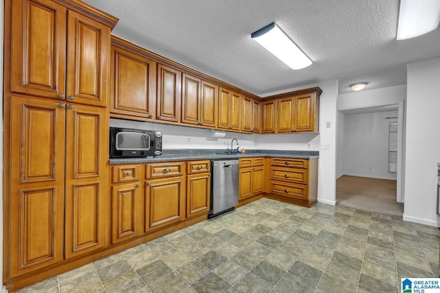 kitchen featuring stainless steel dishwasher, sink, and a textured ceiling