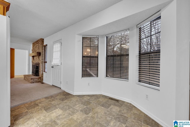 carpeted spare room featuring a textured ceiling and a fireplace