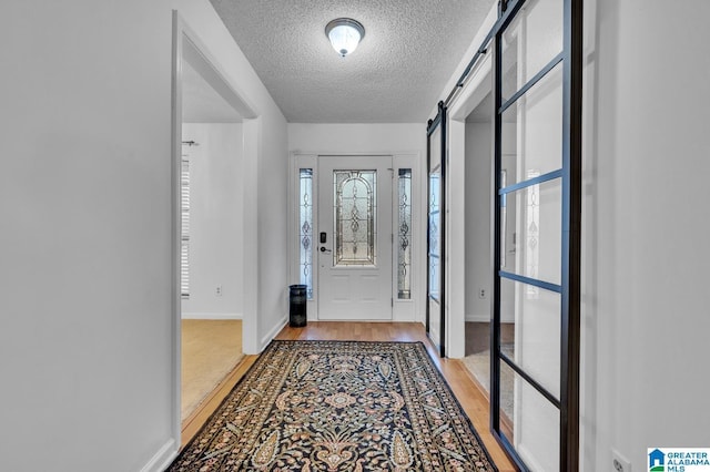 doorway featuring a textured ceiling, a barn door, and light hardwood / wood-style flooring