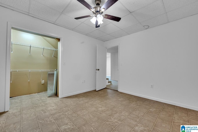 unfurnished bedroom with ceiling fan, a closet, and a drop ceiling