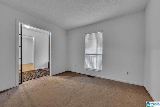 carpeted spare room with a textured ceiling