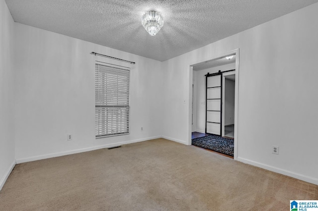 spare room with a barn door, carpet floors, and a textured ceiling