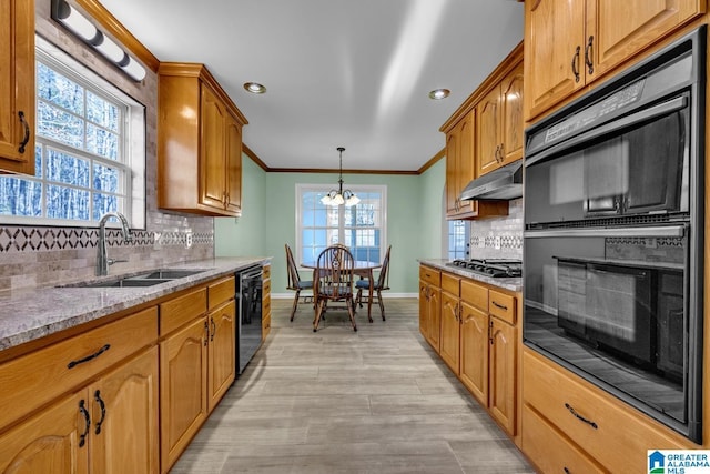 kitchen featuring black appliances, sink, light stone countertops, tasteful backsplash, and a chandelier