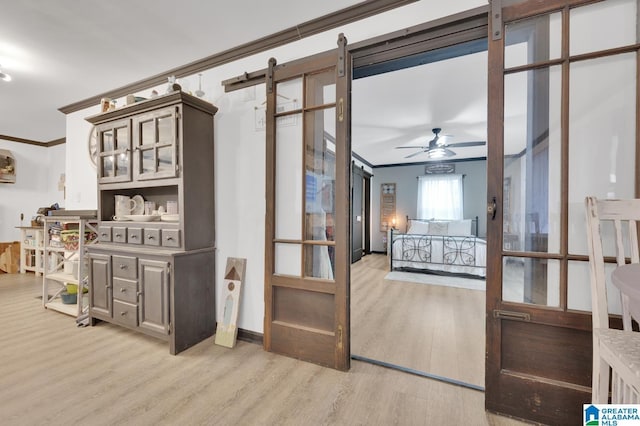 bedroom featuring a barn door, light hardwood / wood-style floors, and ornamental molding