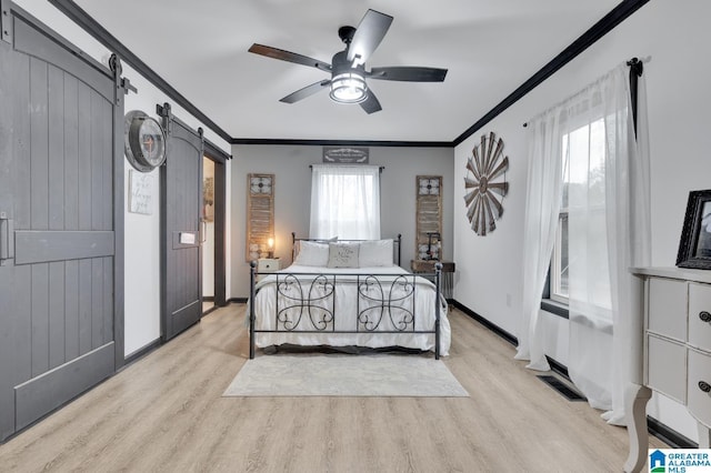 bedroom featuring a barn door, light hardwood / wood-style floors, ceiling fan, and crown molding