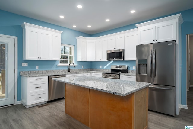 kitchen featuring light stone counters, white cabinetry, stainless steel appliances, and a kitchen island