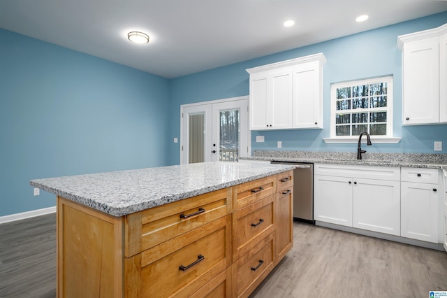 kitchen featuring stainless steel dishwasher, sink, and white cabinets