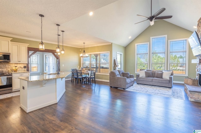 kitchen featuring a center island with sink, light stone countertops, tasteful backsplash, decorative light fixtures, and stainless steel appliances